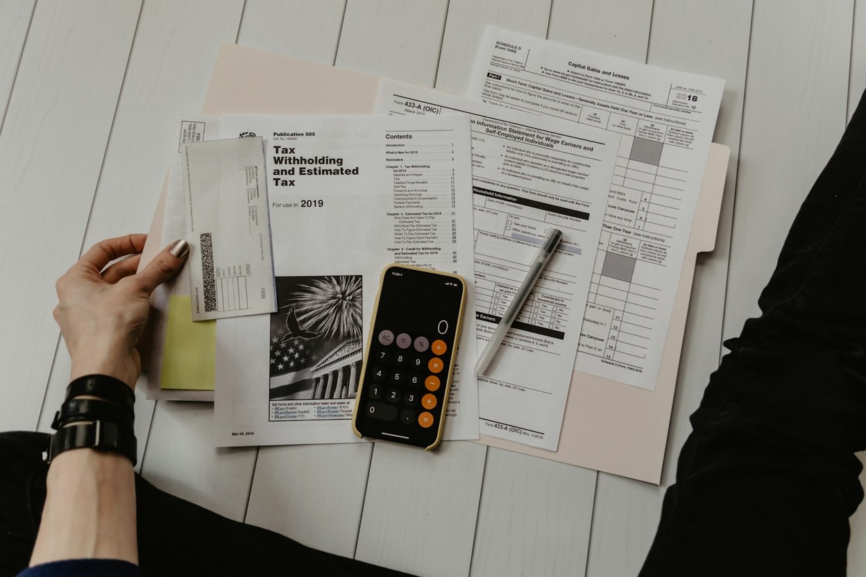 Hands reviewing paperwork and a calculator on a desk — start a lost or damaged card replace.